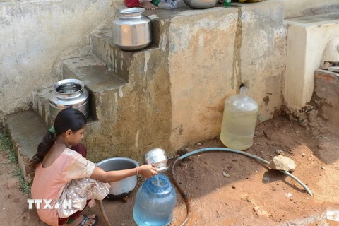 Các em nhỏ lấy nước vào can nhựa từ đường ống cấp nước của chính phủ ở ngoại ô Hyderabad, Ấn Độ. (Nguồn: AFP/TTXVN)