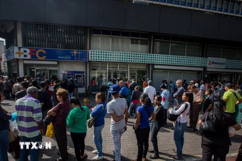 Người dân Venezuela xếp hàng chờ giao dịch bên ngoài Ngân hàng Trung ương ở Caracas. (Nguồn: EPA/TTXVN)