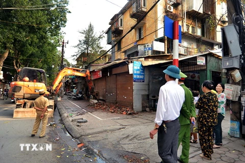 Lực lượng chức năng tiến hành phá bỏ phần diện tích của cửa hàng lấn chiếm vỉa hè trên phố Lương Định Của. (Ảnh: Thành Đạt/TTXVN)