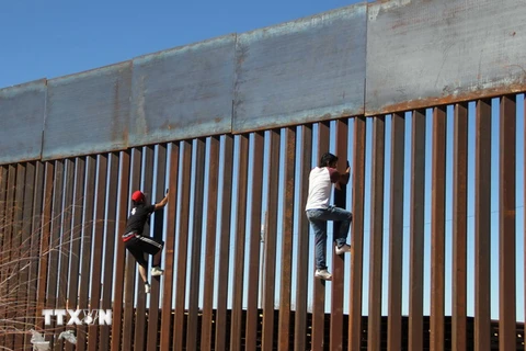 Hai cậu bé cố gắng trèo qua bức tường biên giới giữa Mỹ và Mexico tại Ciudad Juarez, Mexico. (Nguồn: AFP/TTXVN)