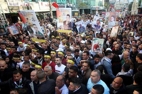 Người Palestine ở Nablus giơ cao những bức ảnh của người thân đang bị giam giữ trong các nhà tù của Israel trong một cuộc míttinh nhân Ngày Tù nhân Palestine. (Nguồn: Xinhua)