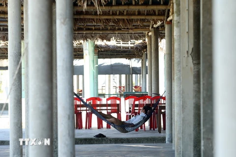 Người dân kinh doanh tại bãi biển Cửa Việt nằm chờ cho qua ngày. (Ảnh: Tuấn Anh/TTXVN)