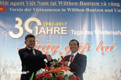 Ông Lê Thanh Hải (trái) - Bí thư thứ nhất Đại sứ quán Việt Nam tại Đức​ - tặng hoa chúc mừng tại buổi gặp mặt. (Ảnh: Thanh Bình/TTXVN)