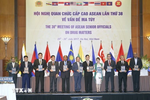Đại biểu nâng bản cam kết về Kế hoạch hành động bảo vệ Cộng đồng ASEAN chống lại hiểm họa ma túy cho giai đoạn 2016-2025. (Ảnh: Doãn Tấn/TTXVN)