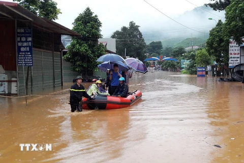 Lực lượng chức năng dùng xuồng đưa người dân vượt qua đoạn ngập sâu tại thị trấn Ít Ong, huyện Mường La. (Ảnh: Nguyễn Cường/TTXVN)
