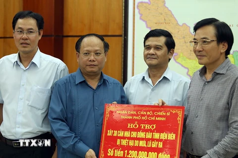 Ông Tất Thành Cang (thứ 2 từ trái sang) trao tặng bảng tượng trưng số tiền hỗ trợ cho đồng bào bị mưa lũ. (Ảnh: Phan Tuấn Anh/TTXVN)