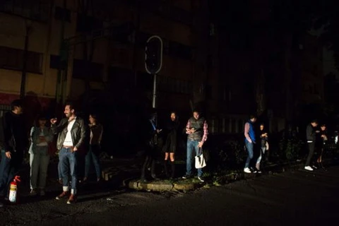 Người dân tại thành phố Mexico City kiểm tra điện thoại của họ trong bóng tối chạy ra khỏi nhà sau khi nghe còi báo động. (Nguồn: AP)