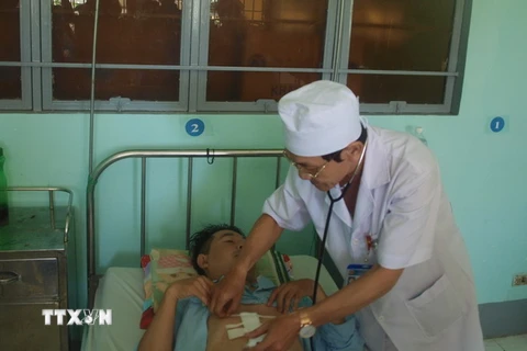 Bác sỹ của Trung tâm y tế huyện Nhơn Trạch khám lại vết thương cho bệnh nhân P.T.T. (Ảnh: Lê Xuân/TTXVN)