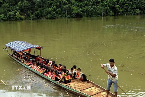Các thầy Trường Phổ thông dân tộc bán trú Tiểu học số 1 xã Ta Gia đưa học sinh vượt sông Nậm Mu về trường. (Ảnh: Việt Hoàng/TTXVN)