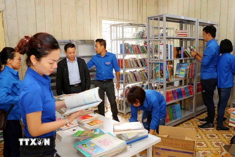 Đoàn viên thanh niên TTXVN chuyển sách lên giá tại thư viện trường Phổ thông Dân tộc bán trú Tiểu học và THCS Phình Hồ. (Ảnh: Thành Đạt/TTXVN)