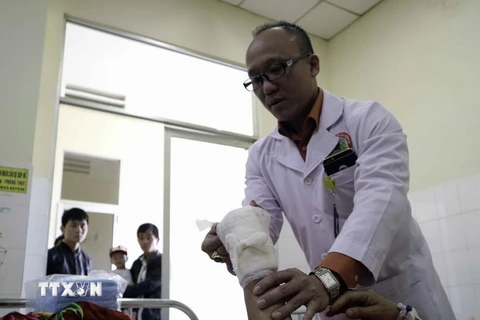 Bác sỹ Phùng Văn Hà, người trực tiếp phẫu thuật, đang kiểm tra bàn tay đã được nối lại của bệnh nhân. (Ảnh: Chu Quốc Hùng/TTXVN)