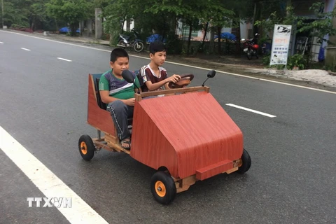 Em Lê Thiên Ân điều khiển chiếc xe ô tô có khung bằng gỗ, chạy bằng nguồn điện ắc quy vừa mới chế tạo. (Ảnh: Hồ Cầu/TTXVN)