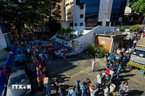 Người dân Venezuela xếp hàng chờ đổi tiền bên ngoài ngân hàng trung ương ở Caracas. (Nguồn: AFP/TTXVN)