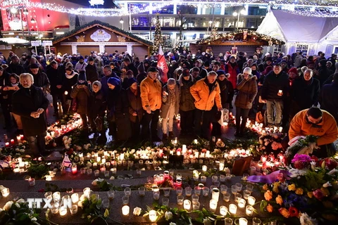 Những người tham dự thắp nến và đặt hoa trước di ảnh của những nạn nhân thiệt mạng trong vụ khủng bố, cùng cầu nguyện cho họ. (Nguồn: AFP/TTXVN)