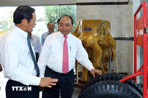 Thủ tướng Nguyễn Xuân Phúc xem các sản phẩm của Tập đoàn công nghiệp cao su Việt Nam. (Ảnh: Thống Nhất/TTXVN)