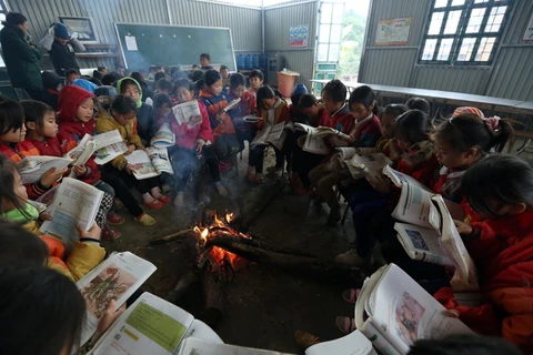 Học sinh nội trú trường Tiểu học Tỏa Tình, huyện Tuần Giáo, Điện Biên ngồi ôn bài bên đống lửa sưởi ấm trong những ngày giá rét. (Ảnh: Phan Tuấn Anh/TTXVN)