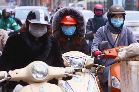 Người dân tại Hà Nội ra đường với trang phục kín mít để tránh rét. (Ảnh: Quang Quyết/TTXVN)