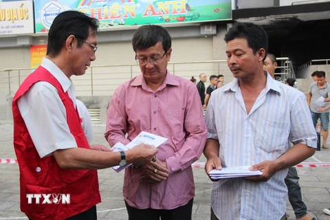 Đại diện Trung ương Hội Chữ thập Đỏ Việt Nam trao hỗ trợ cho gia đình nạn nhân. (Ảnh: Xuân Dự/TTXVN​)