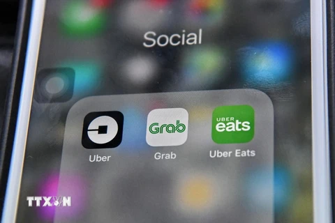 Ứng dụng Grab (giữa) và Uber (trái) trên điện thoại di động. (Nguồn: THX/TTXVN)