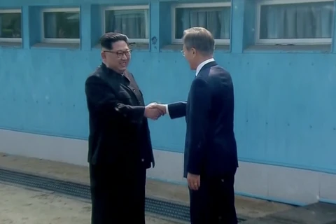 Tổng thống Moon Jae-in và lãnh đạo Kim Jong-un đã bắt tay nhau tại đường ranh giới phân định hai miền. (Nguồn: CNN)