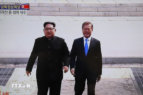 Tổng thống Hàn Quốc Moon Jae-in (phải) và Nhà lãnh đạo Triều Tiên Kim Jong-un bắt tay hữu nghị tại đường ranh giới phân định hai miền. (Nguồn: YONHA/TTXVN)