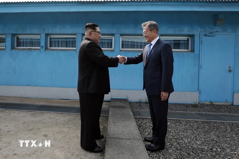 Tổng thống Hàn Quốc Moon Jae-in (phải) đón Nhà lãnh đạo Triều Tiên Kim Jong-un ở đường phân định ranh giới giữa hai miền tại làng đình chiến Panmunjom. (Nguồn: TTXVN)
