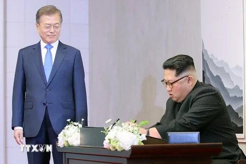 Nhà lãnh đạo Triều Tiên Kim Jong-un (phải) viết sổ lưu bút trước cuộc hội đàm thượng đỉnh với Tổng thống Hàn Quốc Moon Jae-in ở làng đình chiến Panmunjom. (Nguồn: Yonhap/TTXVN)