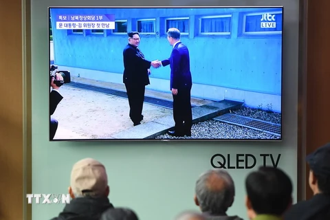 Người dân Hàn Quốc theo dõi hình ảnh Tổng thống Hàn Quốc Moon Jae-in (phải) đón Nhà lãnh đạo Triều Tiên Kim Jong-un ở đường phân định ranh giới giữa hai miền tại làng đình chiến Panmunjom. (Nguồn: AFP/TTXVN)