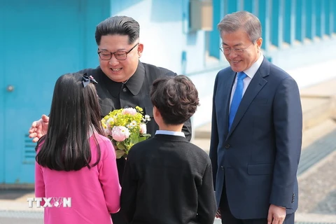 Tổng thống Hàn Quốc Moon Jae-in (phải, phía sau) và Nhà lãnh đạo Triều Tiên Kim Jong-un (trái, phía sau) nhận hoa chúc mừng từ các em thiếu nhi Hàn Quốc tại lễ đón ở quảng trường làng đình chiến Panmunjom. (Nguồn: YONHAP/TTXVN)