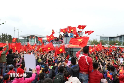 Các cầu thủ U23 Việt Nam trong rừng người hâm mộ vây quanh chào đón. (Ảnh: Quốc Khánh/TTXVN)