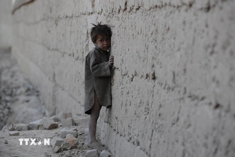 Một em bé Afghanistan đứng dựa vào bức tường khu vực đổ nát do xung đột ở ngoại ô Kabul tháng 10/2011. (Nguồn: AFP/TTXVN)