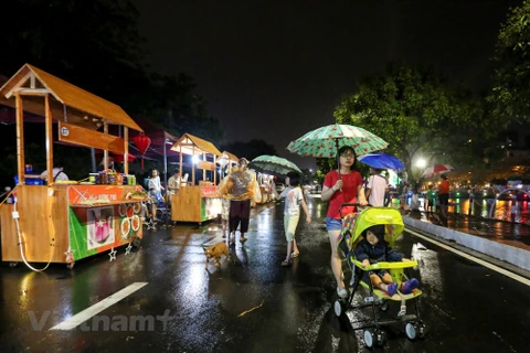 Cơn mưa tầm tã không ngăn được hàng trăm người dân đến thưởng lãm tuyến phố mới của Hà Nội. (Ảnh: Minh Sơn/Vietnam+)