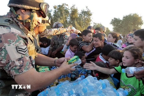 Binh sỹ Jordan phân phát nước uống và lương thực cho người tị nạn Syria tại khu vực Ramtha ở biên giới Syria-Jordan. (Ảnh: AFP/TTXVN)