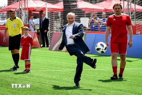 Tổng thống Nga Vladimir Putin (giữa) sút bóng khi ông tham dự lễ khai mạc triển lãm trận đấu bóng đá tại Công viên bóng đá World Cup trên Quảng trường Đỏ ở thủ đô Moskva. (Nguồn: AFP/TTXVN)