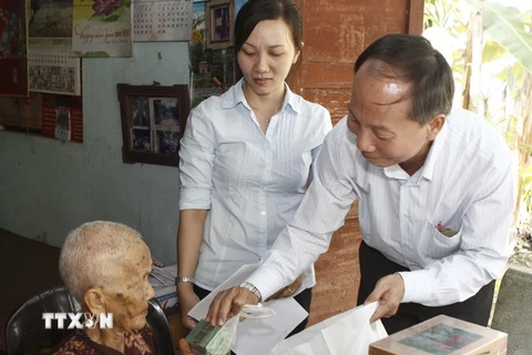 Phó Chủ tịch Ủy ban Mặt trận Tổ quốc Thành phố Hồ Chí Minh Trần Tấn Hùng trao quà cho Mẹ Việt Nam Anh hùng Bùi Thị Diệp. (Ảnh: Hoàng Hải/TTXVN)