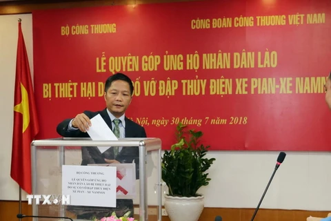 Bộ trưởng Bộ Công Thương Trần Tuấn Anh quyên góp ủng hộ nhân dân Lào. (Ảnh: Trần Việt/TTXVN)