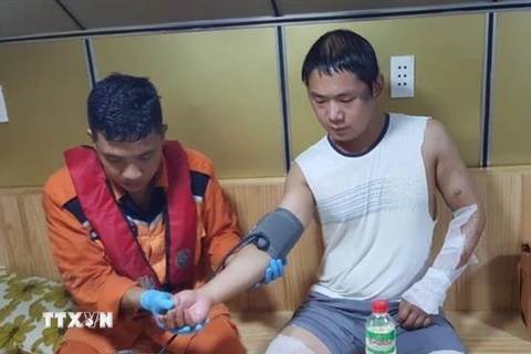 Nhân viên của Trung tâm Phối hợp tìm kiếm, cứu nạn hàng hải Việt Nam kiểm tra sức khỏe nạn nhân (áo trắng bên phải) trên tàu SAR 27-01. (Ảnh: Phan Sáu/TTXVN)