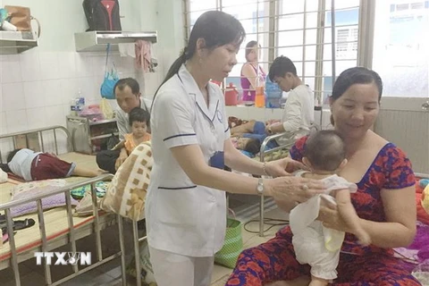 Bác sỹ khoa Nhi thăm khám cho trẻ mắc tay chân miệng. (Ảnh: Nam Thái/TTXVN)