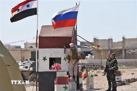 Cờ Syria (trái) và cờ Nga tại khu vực Abu Duhur, tỉnh Idlib. (Nguồn: AFP/TTXVN)