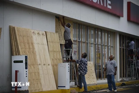 Người dân đóng những tấm gỗ để bảo vệ cửa sổ trước khi bão Willa đổ bộ vào bang Sinaloa, Mexico. (Nguồn: AFP/TTXVN)