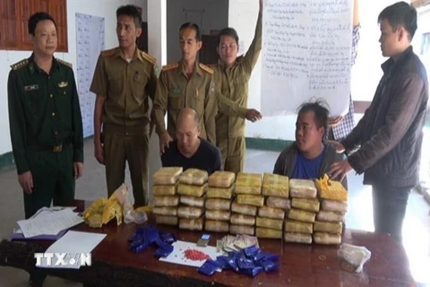Các đối tượng và tang vật bắt giữ trong chuyên án tại cơ quan Ty an ninh Oudomxay, Lào. (Ảnh: TTXVN phát)