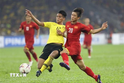 Phan Văn Đức (20) tranh bóng với hậu vệ Malaysia. (Ảnh: Hoàng Linh/TTXVN)