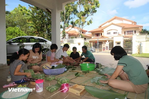 Cháu Nguyễn Như Phú (áo trắng, thứ tư từ trái sang) hoàn thành chiếc bánh chưng tự gói đầu tiên. (Ảnh: Hà Ngọc-Hoàng Nhương/Vietnam+)
