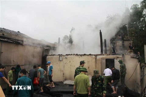 Các lực lượng chức năng tham gia ứng cứu, giúp đỡ các hộ gia đình bị cháy nhà ở thôn Mới, xã Xuân Giang, huyện Quang Bình. (Ảnh: Mộc Lan-TTXVN phát)