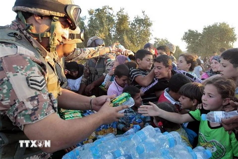Binh sỹ Jordan phân phát nước uống và lương thực cho người tị nạn Syria tại khu vực Ramtha ở biên giới Syria-Jordan. (Nguồn: AFP/TTXVN)