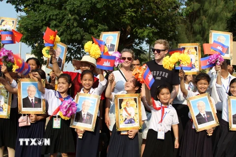 Khách nước ngoài chụp ảnh lưu niệm với các em học sinh Việt kiều tham gia đón đoàn. (Ảnh: Minh Hưng/TTXVN)