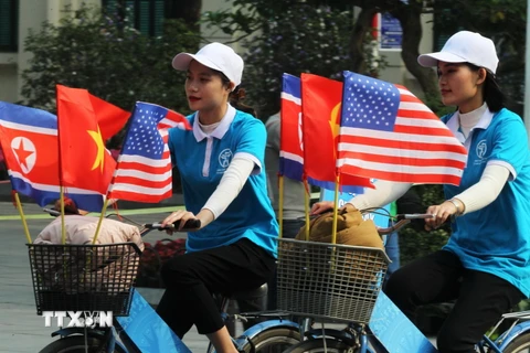 Trong ảnh: Thiếu nữ Việt Nam đạp xe diễu hành với cờ Việt Nam, Mỹ và Triều Tiên trên đường phố Đinh Tiên Hoàng, Hà Nội. (Ảnh: Lâm Khánh/TTXVN)