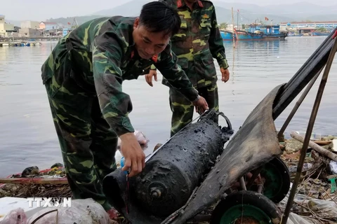 Lực lượng chức năng trục vớt quả ngư lôi lên bờ. (Ảnh: Phước Ngọc/TTXVN)