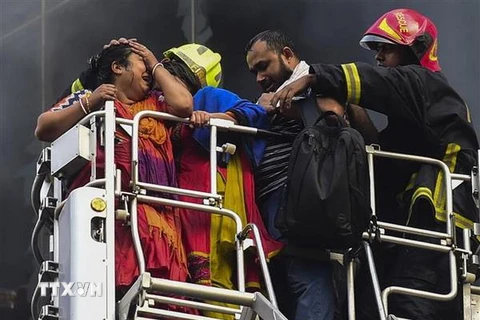 Lực lượng cứu hộ chuyển nạn nhân sống sót tại hiện trường vụ cháy tòa thương mại 22 tầng ở Dhaka ngày 28/3. (Nguồn: AFP/TTXVN)