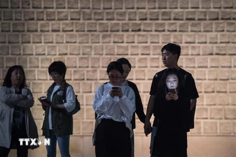 Một nhóm các bạn trẻ sử dụng điện thoại di động tại Seoul, Hàn Quốc. (Nguồn: AFP/TTXVN)